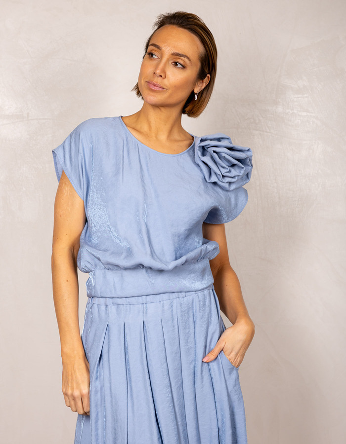 Blauwe top met bloemdetail op de schouder